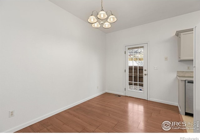 unfurnished dining area with light hardwood / wood-style floors and an inviting chandelier