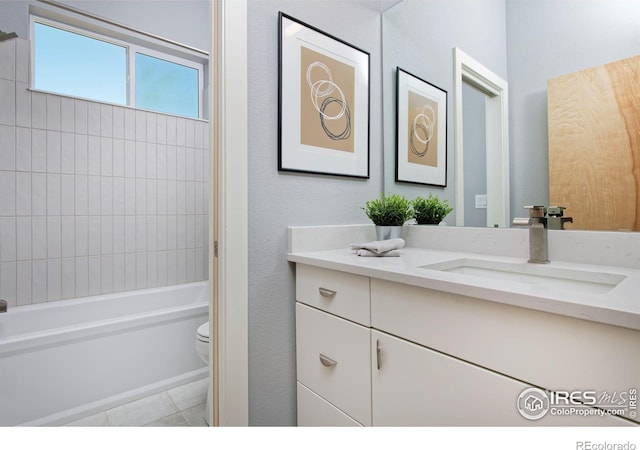 full bathroom with tile patterned floors, tiled shower / bath, vanity, and toilet