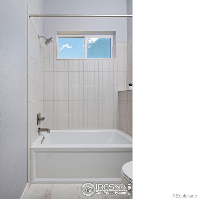 bathroom with tiled shower / bath, tile patterned flooring, and toilet