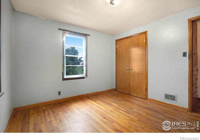 unfurnished bedroom featuring a closet and hardwood / wood-style flooring