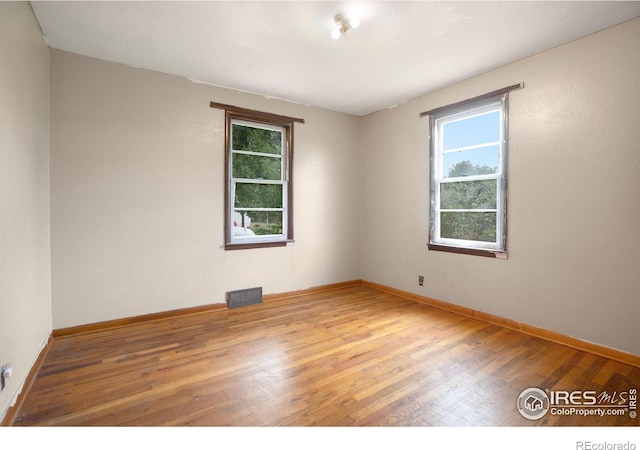 spare room featuring plenty of natural light and hardwood / wood-style floors