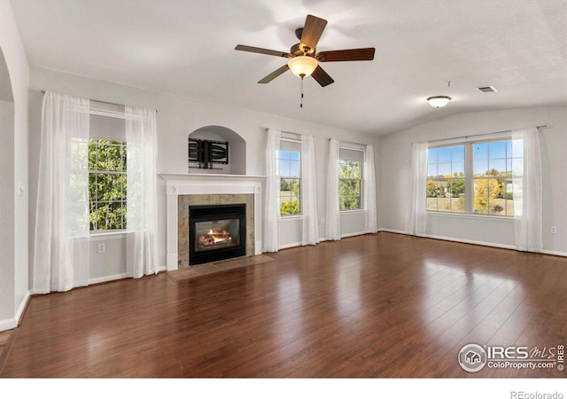 unfurnished living room with plenty of natural light, dark hardwood / wood-style flooring, a tiled fireplace, and vaulted ceiling