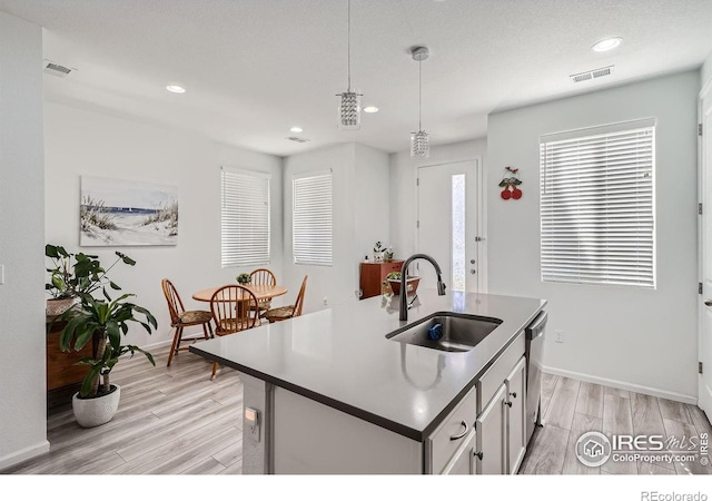 kitchen featuring an island with sink, light wood-type flooring, dishwasher, and sink