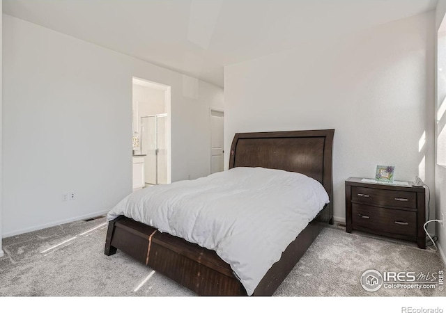 bedroom featuring connected bathroom and light colored carpet