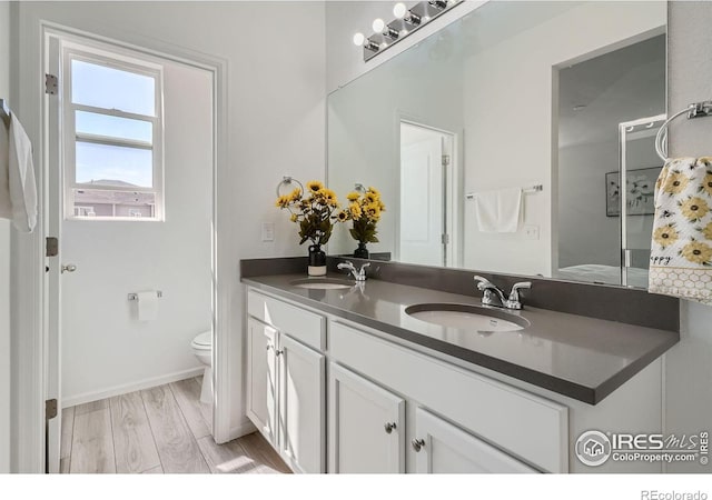 bathroom featuring wood-type flooring, vanity, and toilet