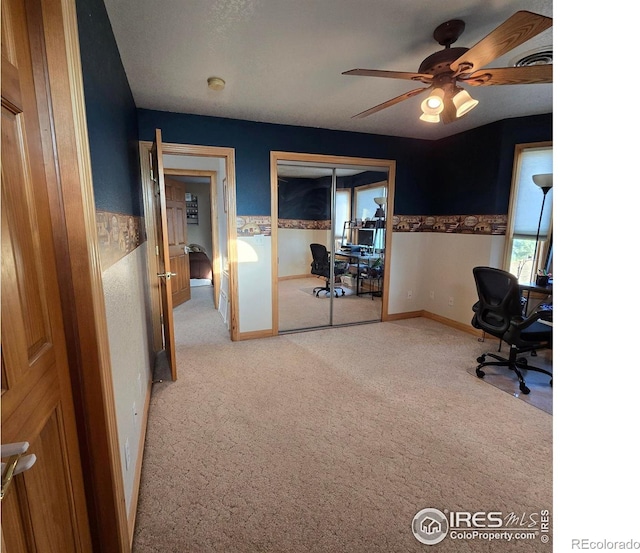 carpeted office space featuring ceiling fan