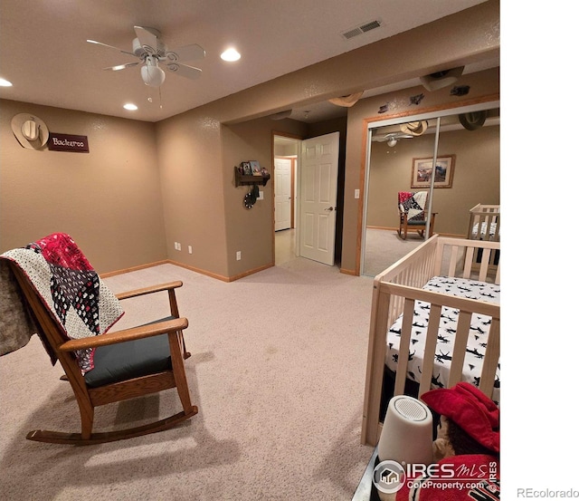 bedroom with a closet, ceiling fan, carpet, and a crib