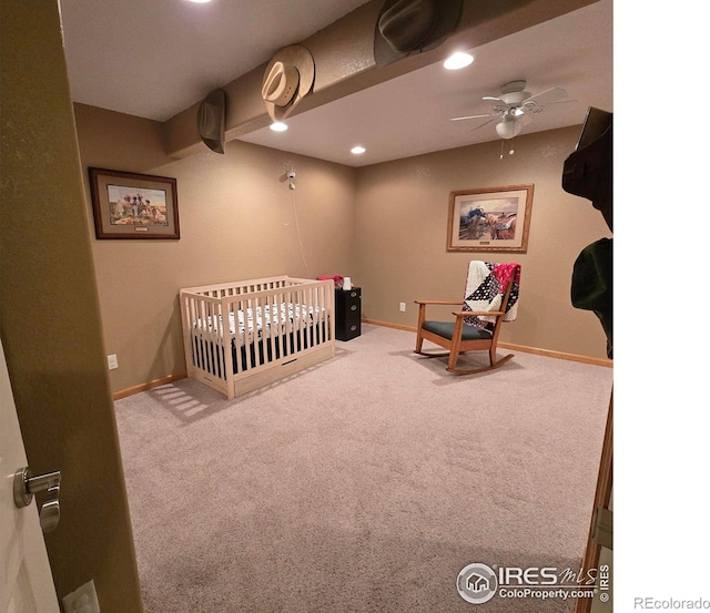 bedroom featuring ceiling fan, carpet, and a crib