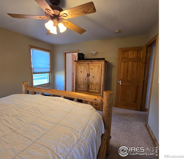 bedroom featuring a textured ceiling, light colored carpet, and ceiling fan