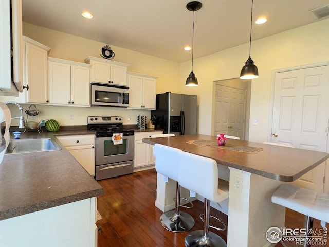 kitchen featuring white cabinets, pendant lighting, dark wood-type flooring, appliances with stainless steel finishes, and a center island