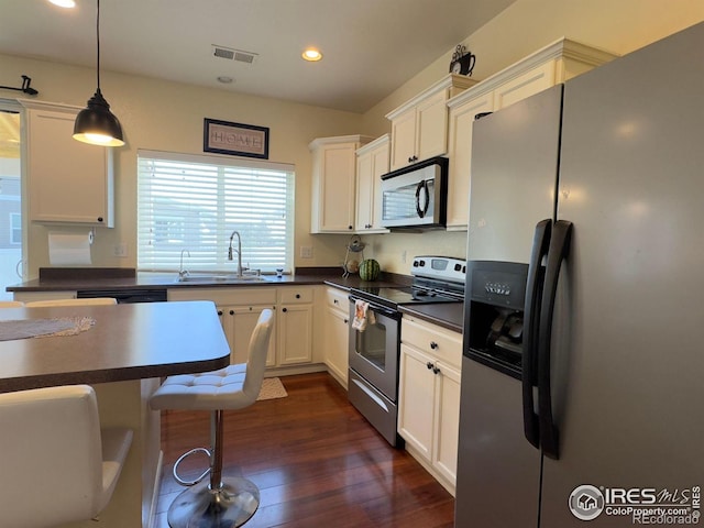 kitchen with pendant lighting, stainless steel appliances, dark wood-type flooring, and white cabinets