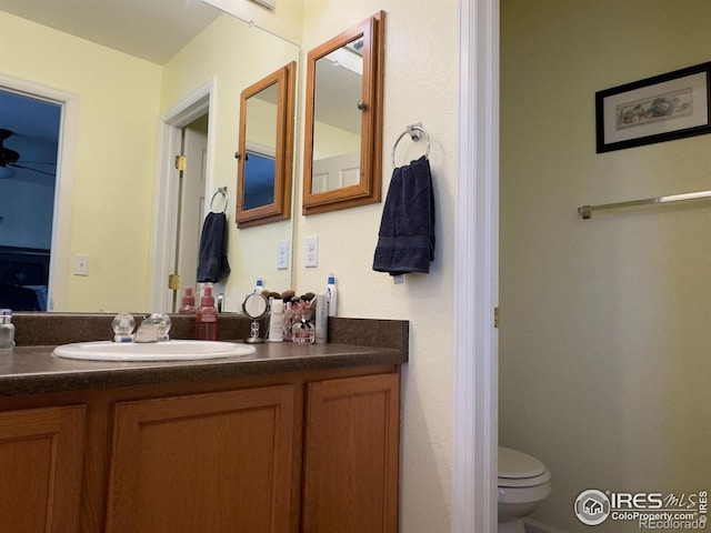 bathroom with vanity, toilet, and ceiling fan