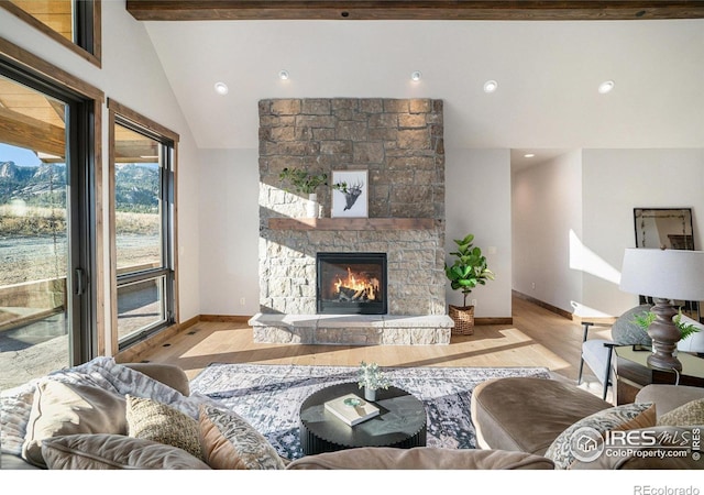 living room featuring light hardwood / wood-style flooring, beam ceiling, high vaulted ceiling, and a stone fireplace