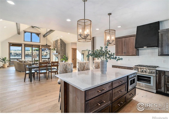 kitchen featuring lofted ceiling with beams, light hardwood / wood-style floors, wall chimney range hood, stainless steel appliances, and decorative light fixtures