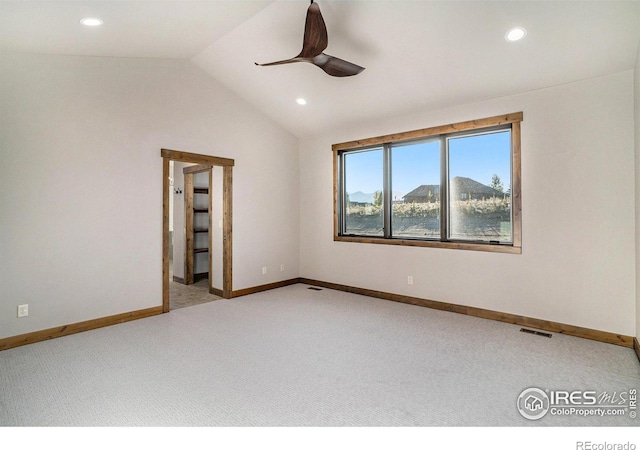 spare room with light carpet, a mountain view, vaulted ceiling, and ceiling fan