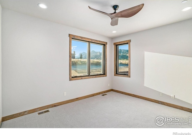 empty room featuring ceiling fan, carpet flooring, and a water view