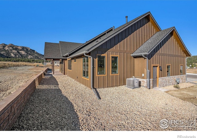 view of side of home with central AC unit, a mountain view, and a patio area