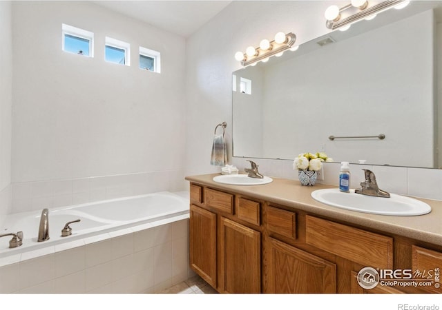 bathroom featuring tiled tub and vanity