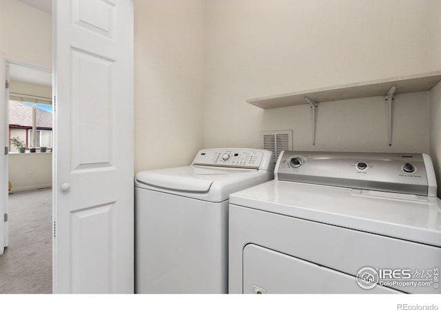 laundry room with washer and dryer and light carpet