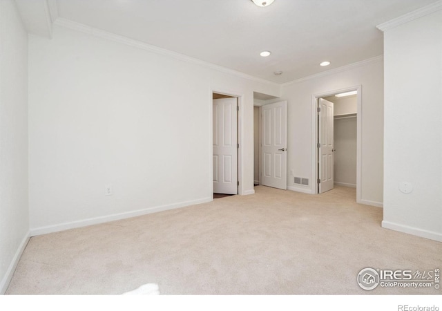 unfurnished bedroom with a spacious closet, light colored carpet, and crown molding