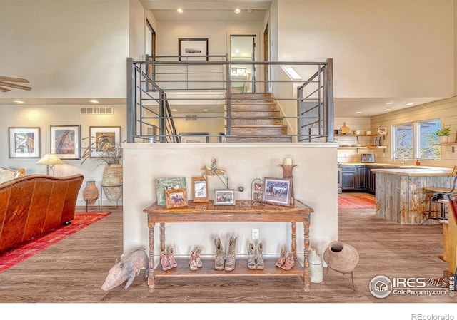 staircase with a high ceiling, hardwood / wood-style floors, and sink