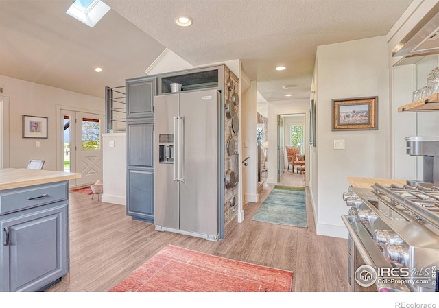 kitchen with light hardwood / wood-style floors, a skylight, gray cabinetry, high end appliances, and a textured ceiling