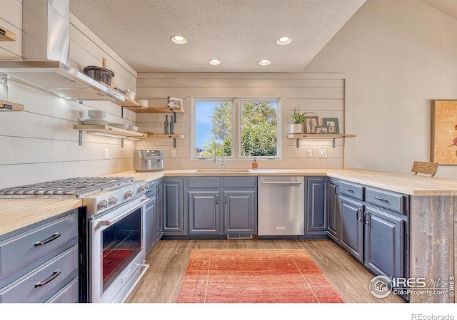 kitchen with stainless steel appliances, hardwood / wood-style flooring, sink, wood counters, and a textured ceiling