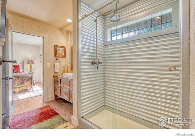 bathroom with an enclosed shower, vanity, and wood-type flooring