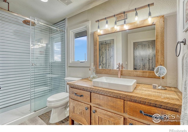 bathroom featuring vanity, a shower with shower door, toilet, and a textured ceiling