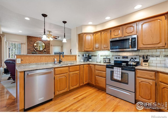 kitchen featuring light wood-type flooring, kitchen peninsula, sink, and stainless steel appliances