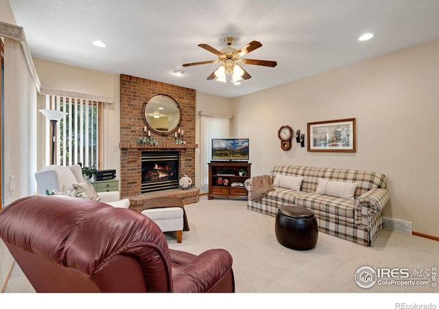 carpeted living room with ceiling fan and a brick fireplace