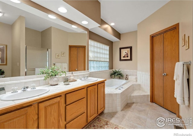 bathroom featuring tile patterned flooring, tiled tub, and vanity