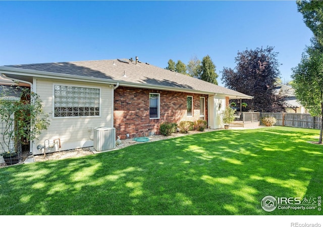 rear view of house with cooling unit and a yard