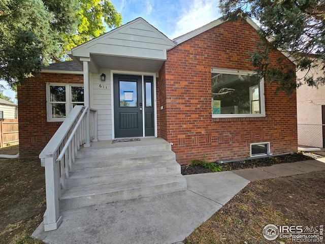 property entrance featuring brick siding and fence