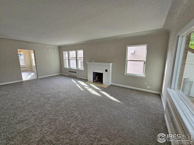 unfurnished living room with a textured ceiling, a fireplace with flush hearth, carpet floors, and baseboards