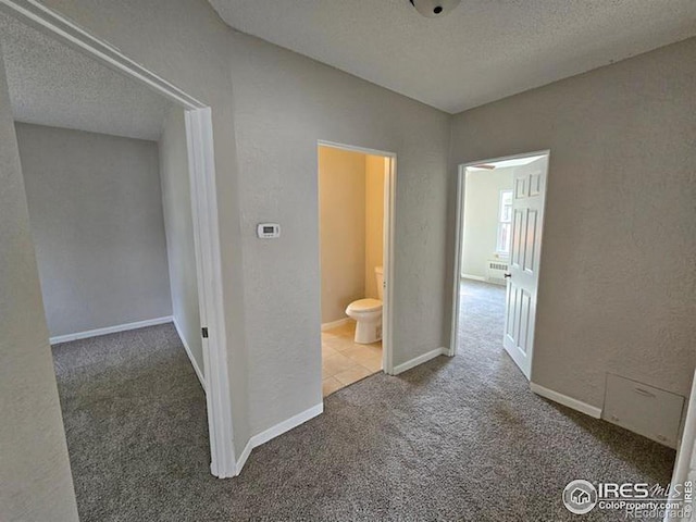 corridor with carpet flooring, a textured ceiling, and baseboards