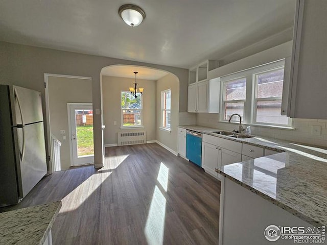 kitchen with sink, white cabinetry, appliances with stainless steel finishes, decorative light fixtures, and radiator heating unit