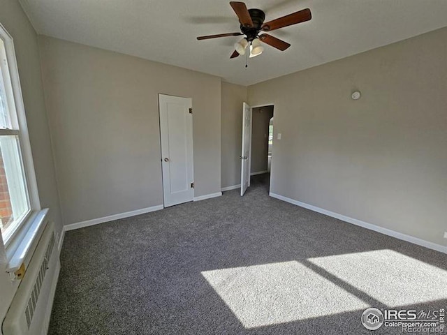 carpeted empty room featuring a ceiling fan and baseboards