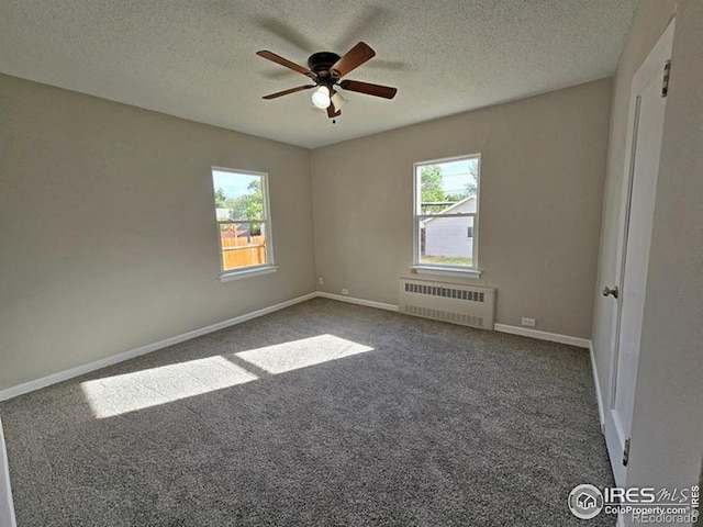 carpeted spare room featuring ceiling fan, radiator, a textured ceiling, and plenty of natural light