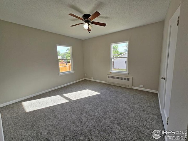empty room featuring radiator heating unit, a textured ceiling, ceiling fan, carpet floors, and baseboards