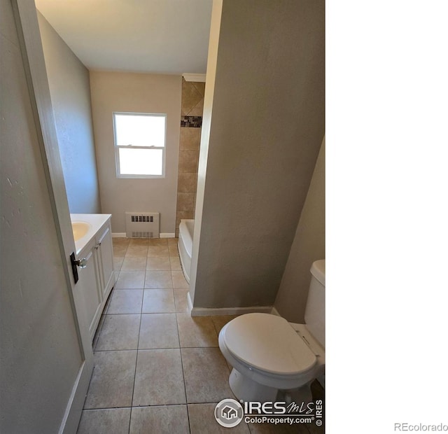 bathroom featuring vanity, radiator heating unit, tiled shower, tile patterned floors, and toilet