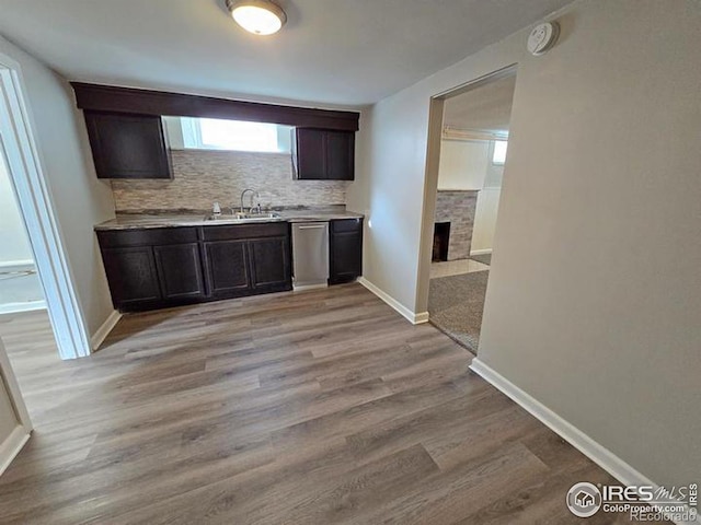 kitchen with light hardwood / wood-style floors, tasteful backsplash, dark brown cabinetry, stainless steel dishwasher, and sink