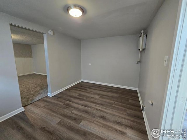 spare room with a textured ceiling and dark hardwood / wood-style flooring