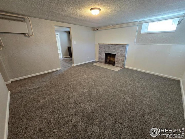 unfurnished living room with a textured ceiling, a tiled fireplace, and dark colored carpet