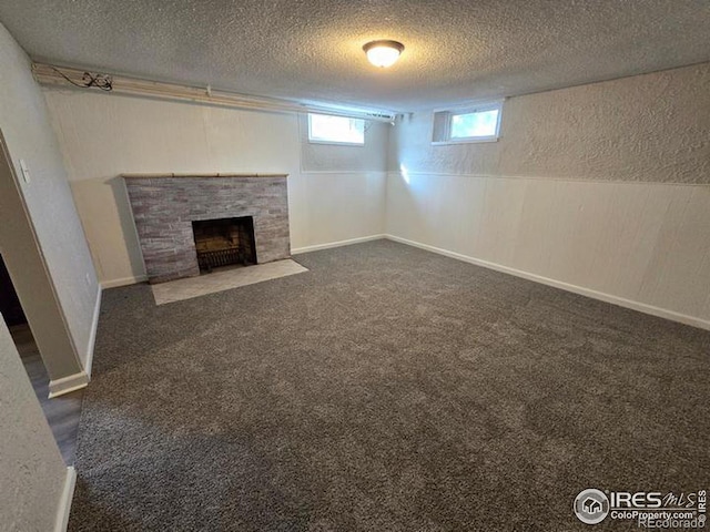 below grade area featuring a textured ceiling, a fireplace, dark carpet, and a textured wall