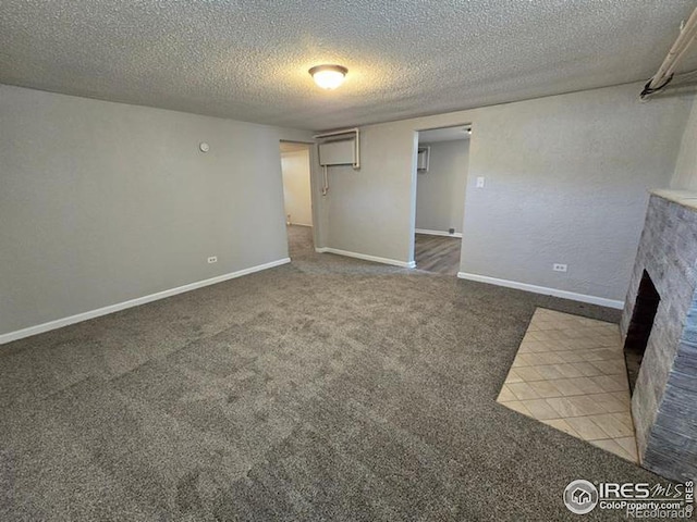 unfurnished living room with carpet floors, a textured ceiling, a brick fireplace, and baseboards