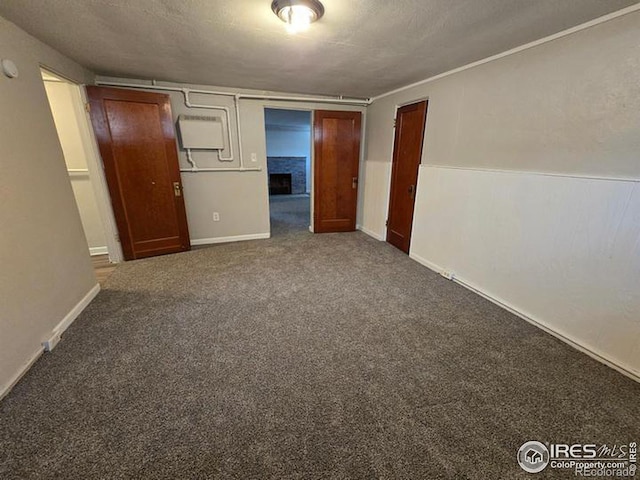 carpeted empty room with a fireplace and baseboards