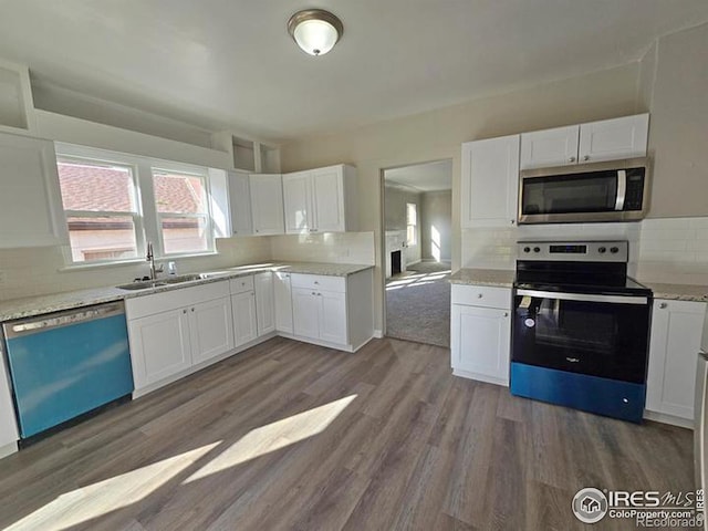 kitchen with stainless steel appliances, a sink, dark wood-style flooring, backsplash, and white cabinets