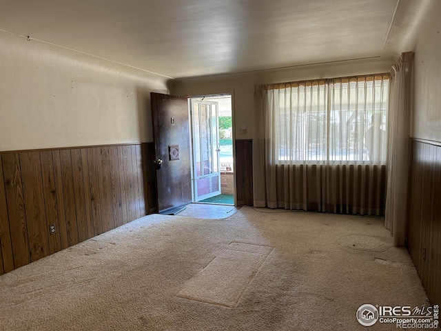 entryway with light colored carpet and wood walls