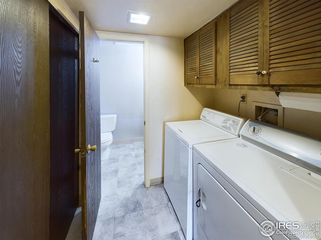 clothes washing area with separate washer and dryer and cabinets